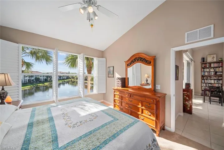 Bedroom with light tile patterned floors, a water view, high vaulted ceiling, and ceiling fan