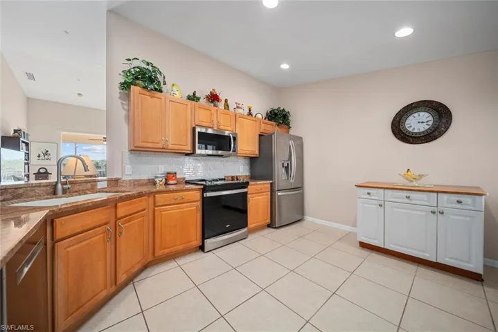 Kitchen with light tile patterned flooring, sink, appliances with stainless steel finishes, and tasteful backsplash