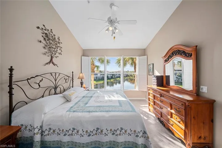 Bedroom with ceiling fan, a water view, carpet floors, and vaulted ceiling