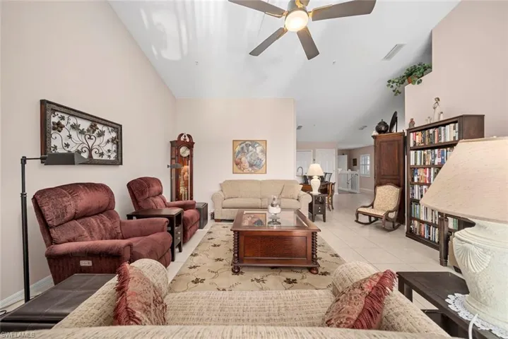 Tiled living room with ceiling fan and vaulted ceiling