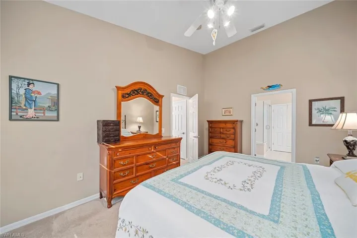 Bedroom featuring ceiling fan, a towering ceiling, and light carpet
