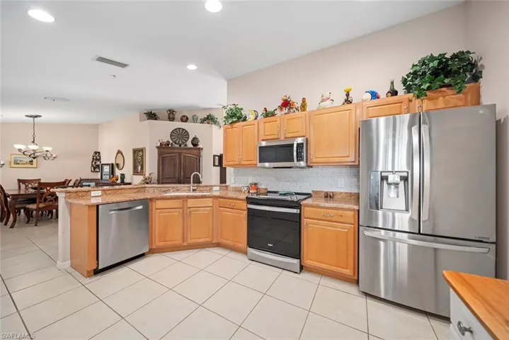 Kitchen featuring appliances with stainless steel finishes, backsplash, sink, a chandelier, and light tile patterned flooring