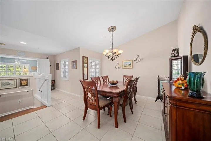 Tiled dining room featuring a healthy amount of sunlight and ceiling fan with notable chandelier