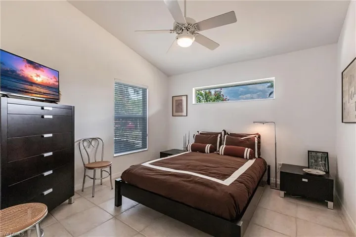 Bedroom featuring light tile patterned floors, lofted ceiling, baseboards, and ceiling fan