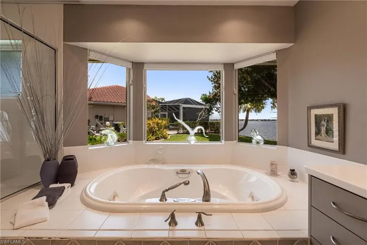 Bathroom with a jetted tub, a water view, and vanity