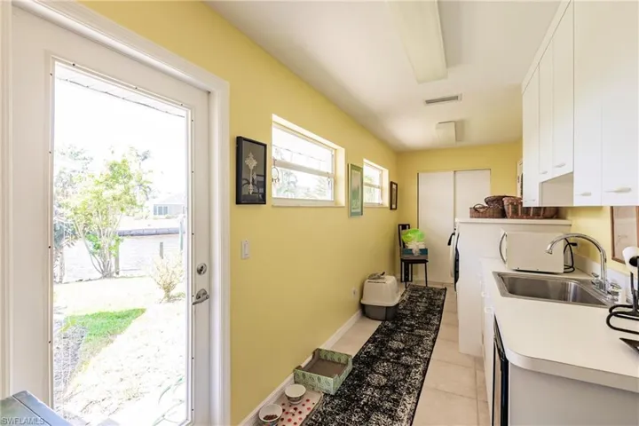Kitchen featuring a sink, white cabinetry, light countertops, light tile patterned floors, and baseboards
