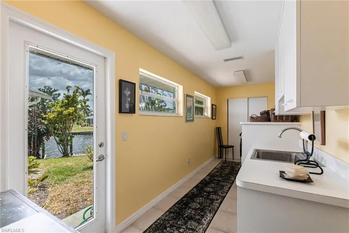 Doorway to outside with a sink, healthy amount of natural light, a water view, and light tile patterned flooring