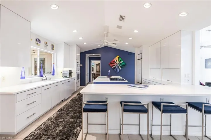 Kitchen with modern cabinets, white cabinets, a sink, a kitchen breakfast bar, and recessed lighting