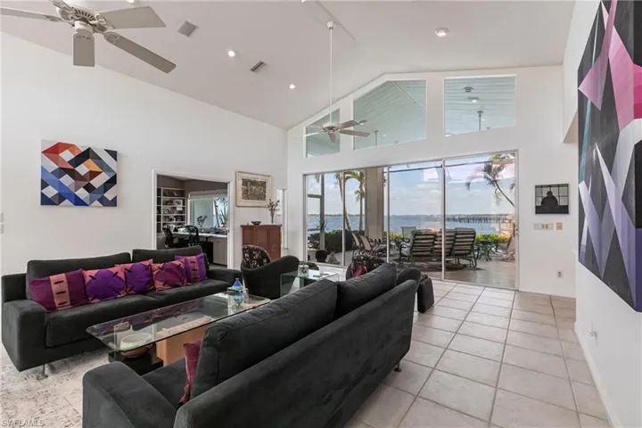 Living area featuring ceiling fan, high vaulted ceiling, light tile patterned floors, baseboards, and recessed lighting
