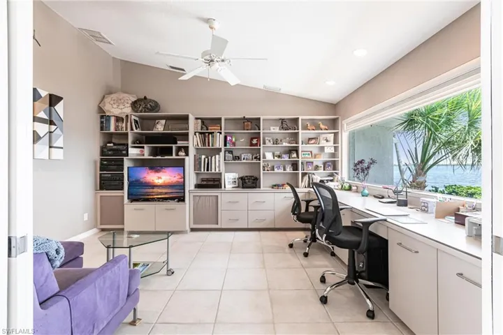 Office featuring vaulted ceiling, ceiling fan, built in desk, light tile patterned flooring, and recessed lighting