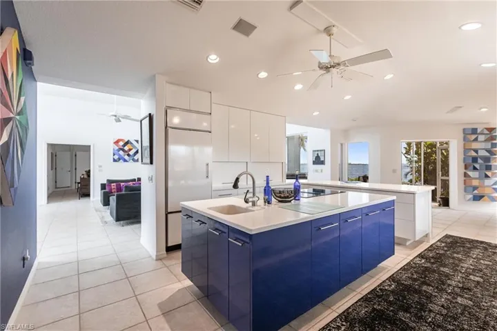 Kitchen featuring modern cabinets, a ceiling fan, an island with sink, a sink, and blue cabinetry