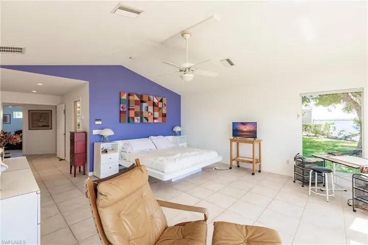 Bedroom with vaulted ceiling, light tile patterned floors, and ceiling fan