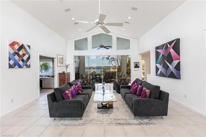 Living area with light tile patterned floors, healthy amount of natural light, high vaulted ceiling, ceiling fan, and recessed lighting