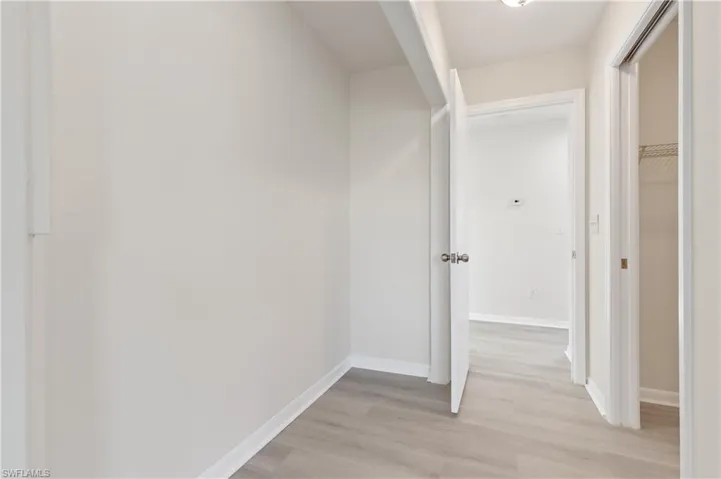 Primary hallway featuring light wood-style flooring and baseboards