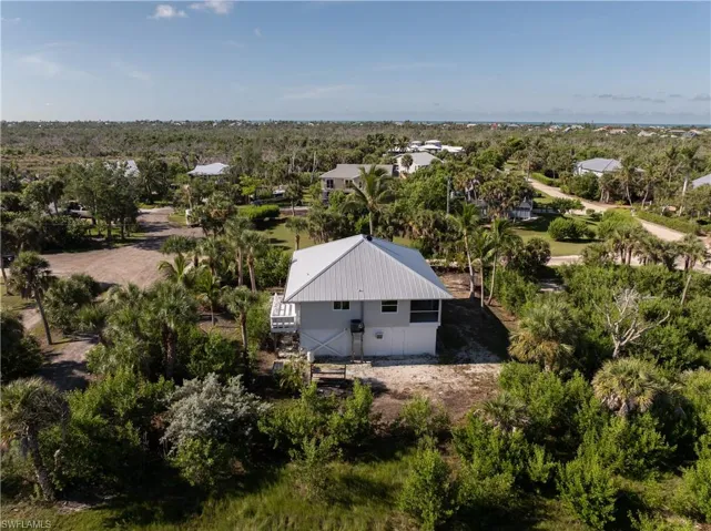 Aerial view of property and surrounding area with a tree filled landscape