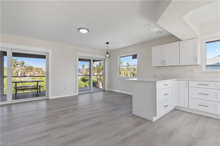 Kitchen with white cabinetry, a peninsula, pendant lighting, light LVP flooring, and recessed lighting