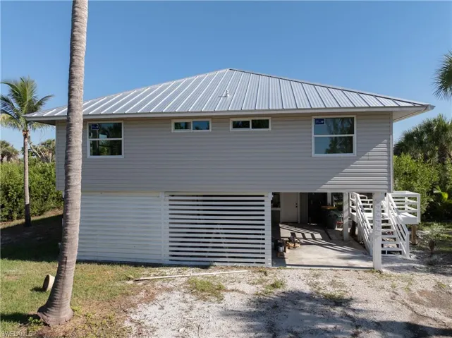 Side view of property with a metal roof, a carport, driveway, and stairs