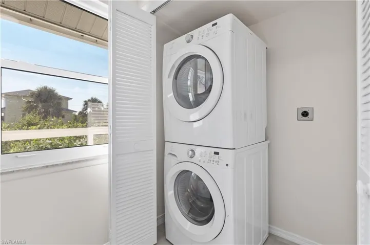 Laundry room featuring estacked washer and dryer and healthy amount of natural light