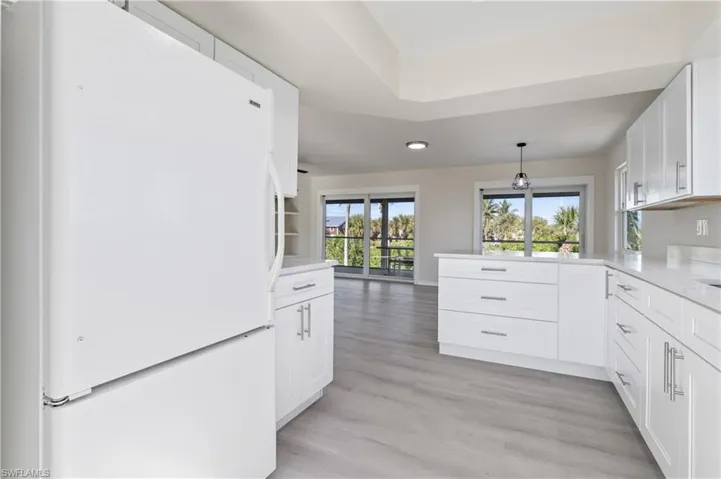 Kitchen with freestanding refrigerator, white cabinetry, hanging light fixtures, light wood-type flooring, and recessed lighting