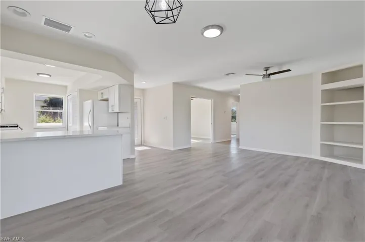 Unfurnished living room with built in shelves, light wood-type flooring, recessed lighting, and a ceiling fan