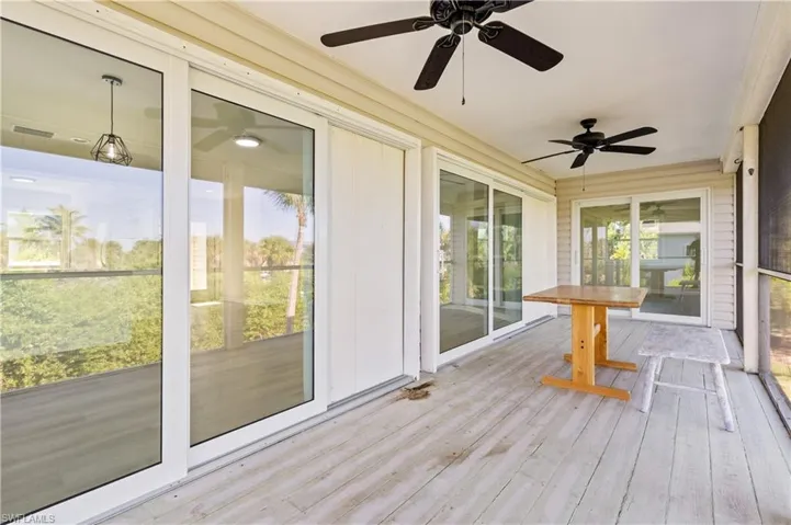Unfurnished screened balcony with ceiling fans, Hurricane impact sliders.
