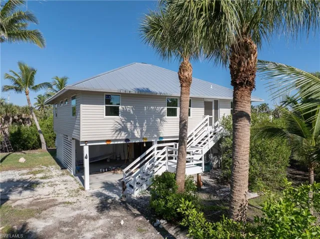 Front view of house featuring stairway and a metal roof