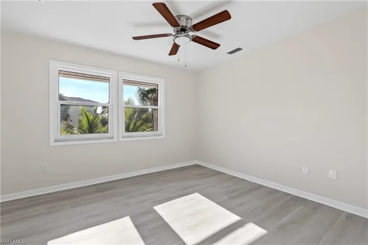 Quest bedroom 1 with light wood-style floors and a ceiling fan