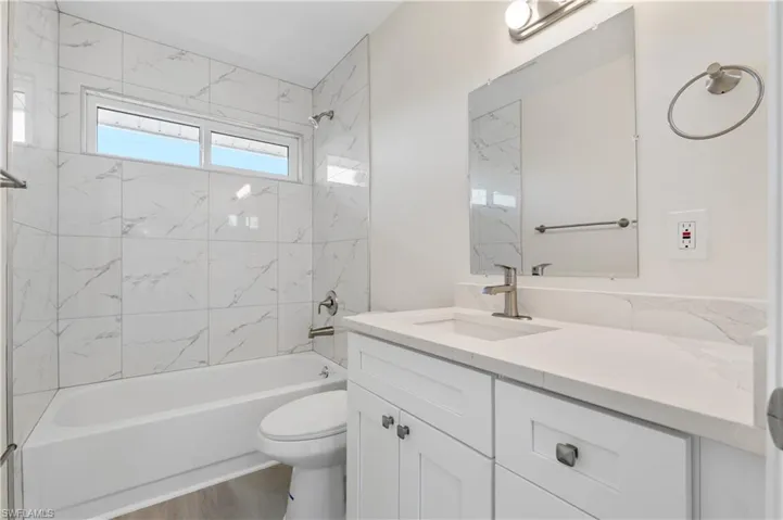 Full bath featuring shower / bath combination, vanity, and wood finished floors