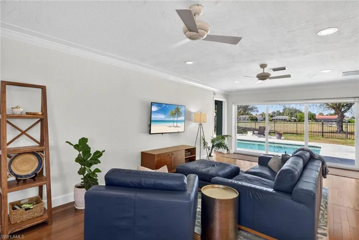 Living room featuring crown molding, wood-type flooring, a ceiling fan, and a textured ceiling