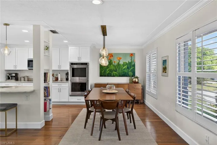 Dining space featuring dark wood-type flooring, recessed lighting, and crown molding