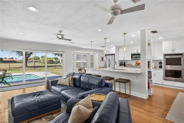 Living room featuring a ceiling fan, light wood finished floors, a textured ceiling, and recessed lighting