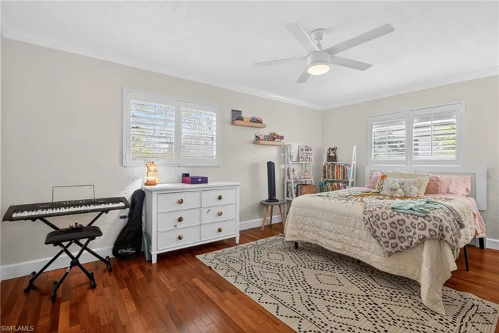Bedroom with dark wood-style flooring, crown molding, and ceiling fan