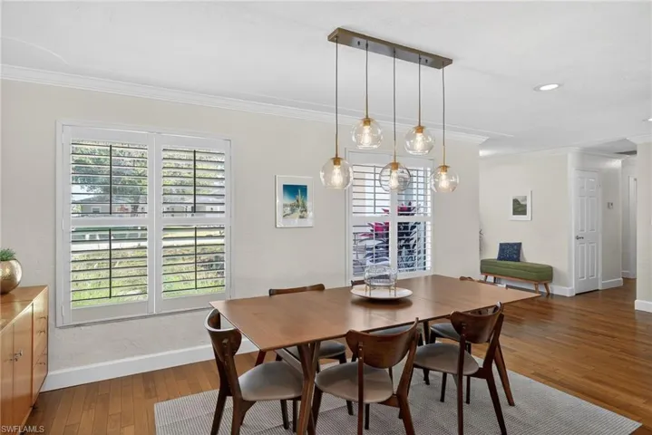 Dining area featuring ornamental molding and dark wood-style floors
