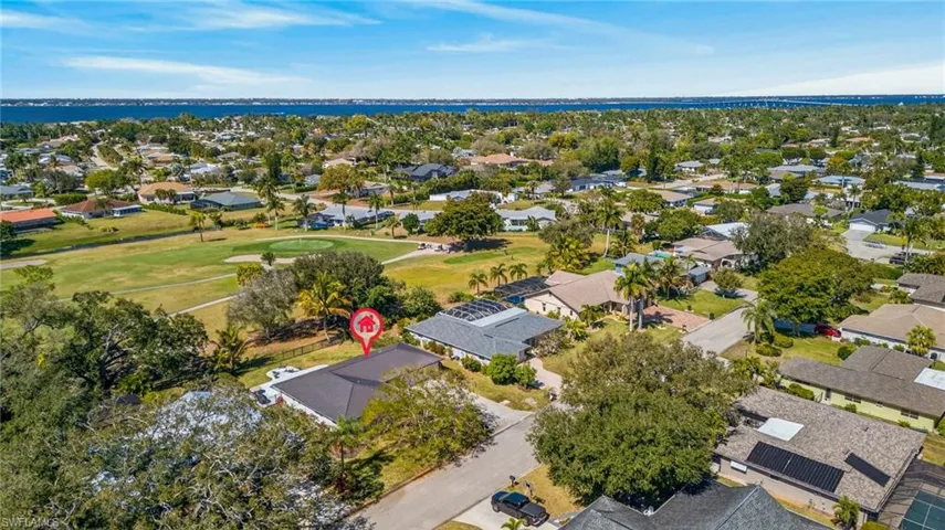 Aerial view of residential area with a nearby body of water and a local golf course