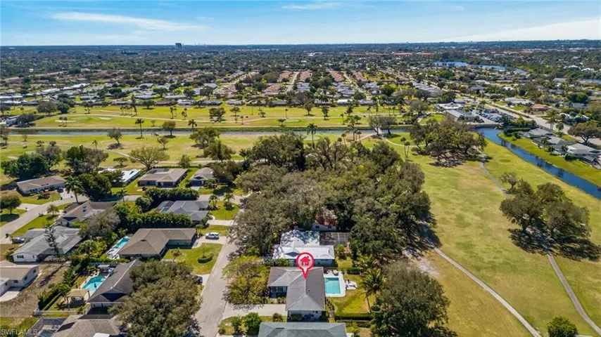 Aerial view of property and surrounding area featuring nearby suburban area, a large body of water, and a golf club