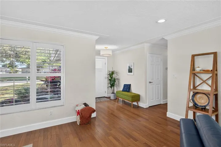 Living area with dark wood-style flooring, ornamental molding, and a textured ceiling