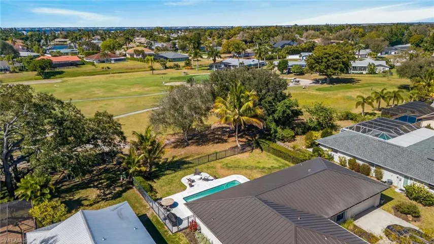 Aerial perspective of suburban area featuring a golf course and a pool