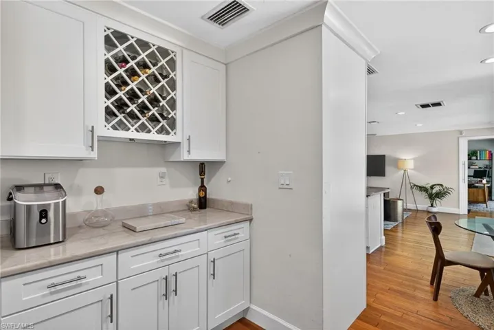 Bar with white cabinetry, light wood-style flooring, recessed lighting, and light stone counters
