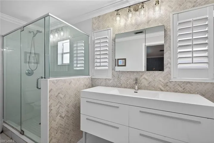 Full bath featuring vanity, crown molding, a shower stall, and tile walls