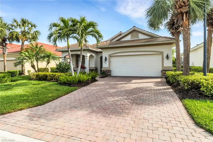 View of front of house with decorative driveway, stucco siding, stone siding, a front lawn, and an attached garage