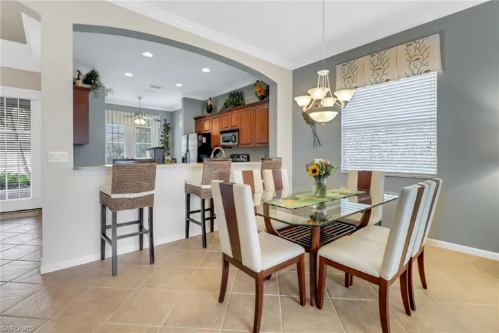 Dining space with a chandelier, ornamental molding, recessed lighting, light tile patterned floors, and arched walkways