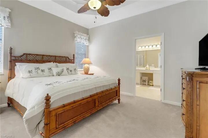 Bedroom featuring light colored carpet, a ceiling fan, a raised ceiling, and ornamental molding
