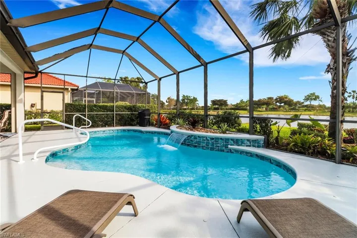 Outdoor pool with a sunroom, glass enclosure, a water view, and a patio area