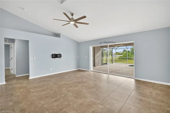 Empty room with lofted ceiling, ceiling fan, and light tile patterned floors