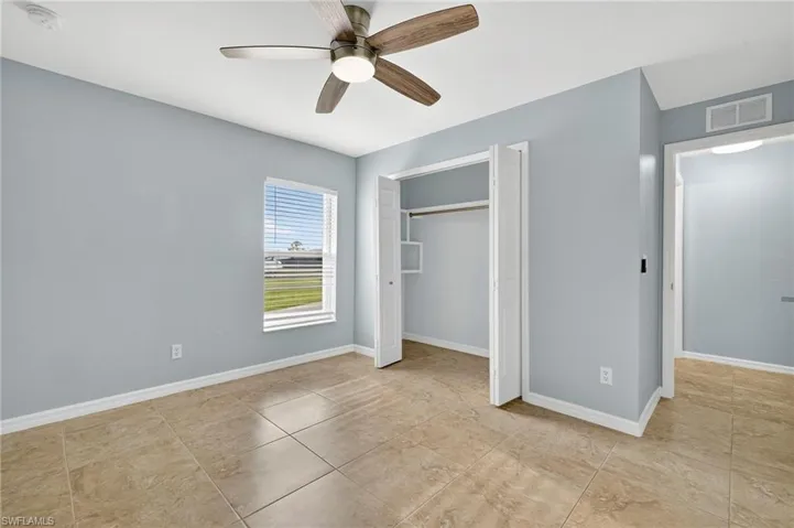 Unfurnished bedroom with ceiling fan, a closet, and light tile patterned flooring