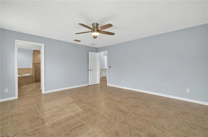 Unfurnished bedroom with a ceiling fan, connected bathroom, and light tile patterned flooring