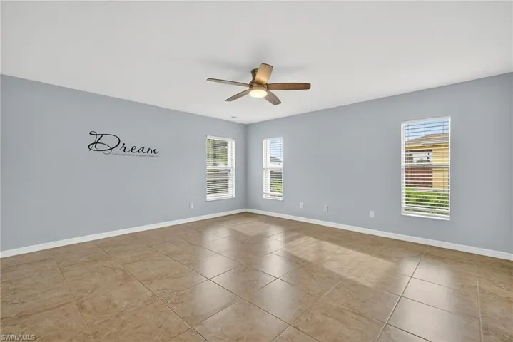 Empty room featuring plenty of natural light, light tile patterned floors, and a ceiling fan