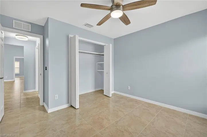 Unfurnished bedroom with ceiling fan, a closet, and light tile patterned floors