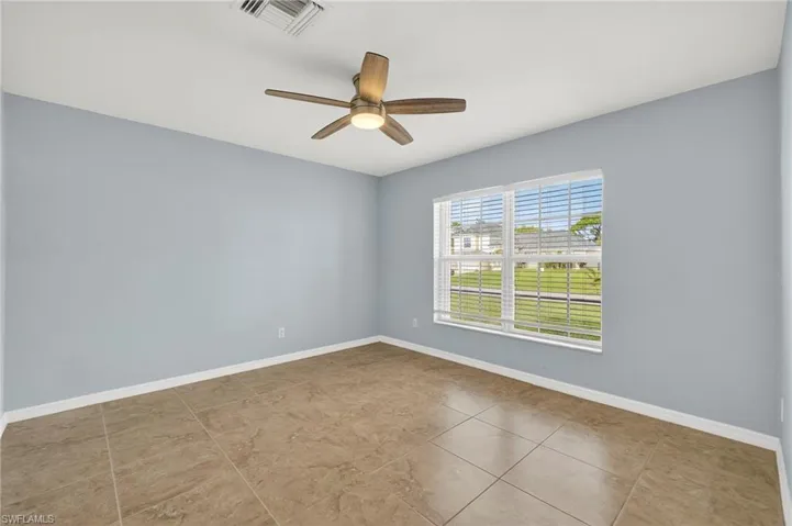 Empty room featuring a ceiling fan and light tile patterned floors