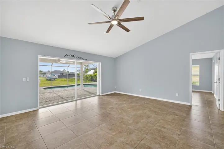 Tiled empty room featuring a sunroom, high vaulted ceiling, and ceiling fan